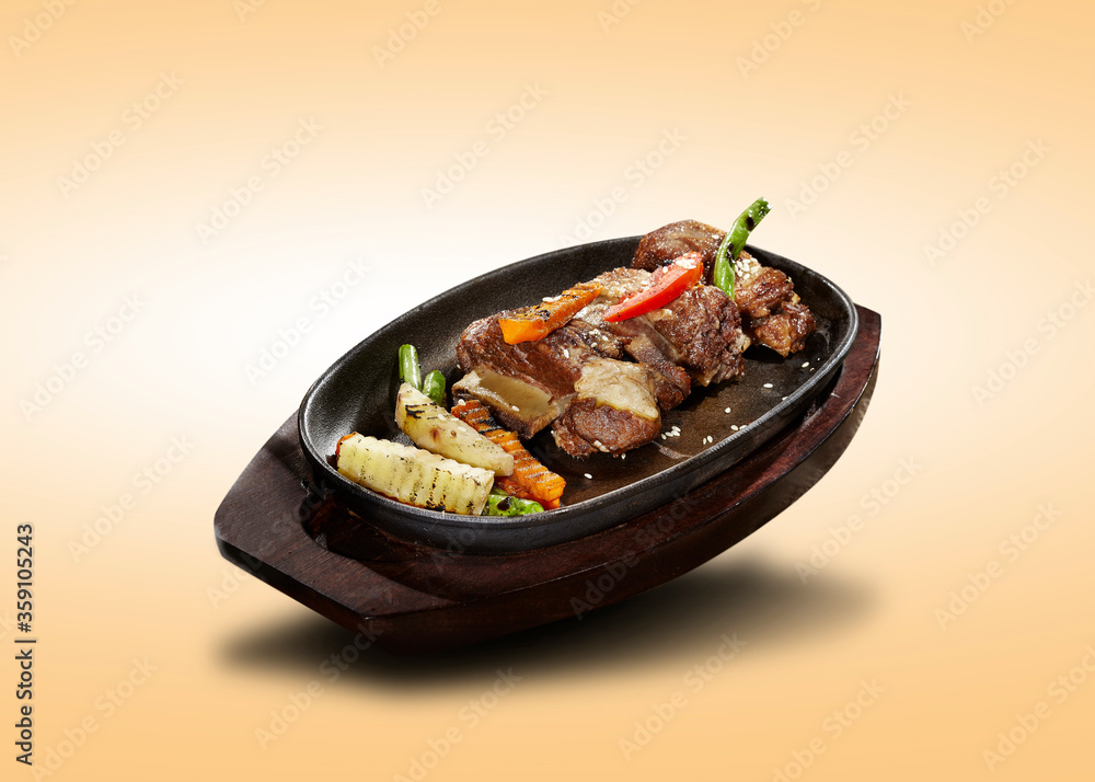 Grilled ribs with potatoes, carrots, beans, served on a hot plate