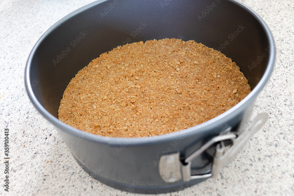 A graham cracker crust pressed into a silver metal spring form pan. A graham cracker crust pressed into a silver metal spring form pan.