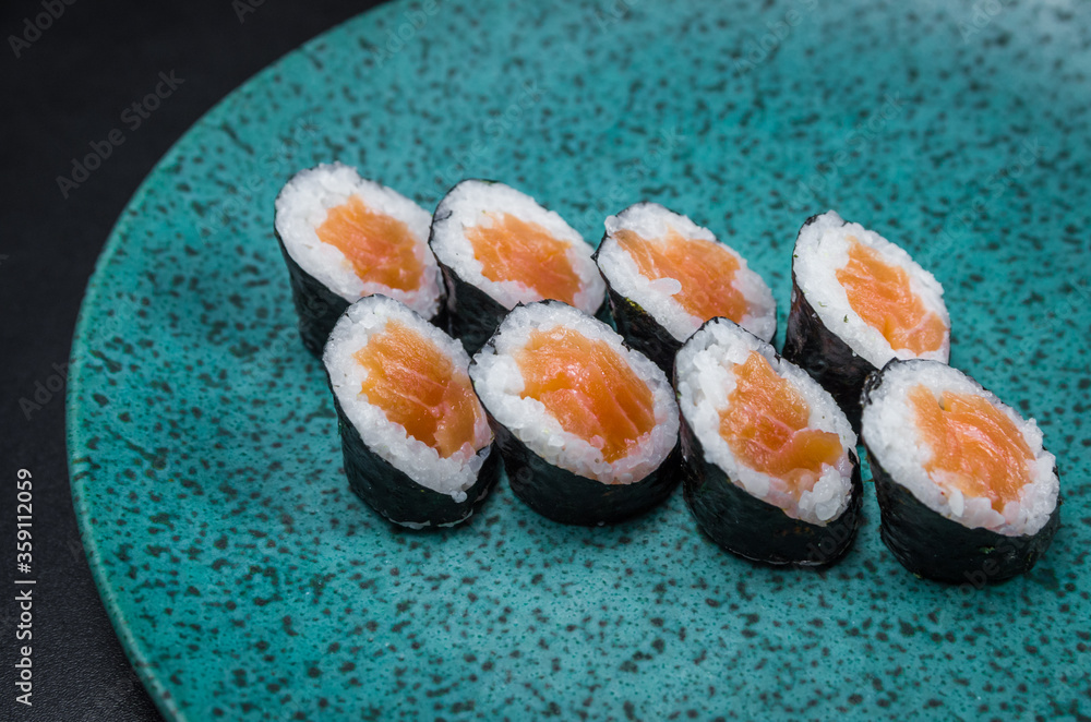 Sushi, traditional Japanese cuisine. Delicious hossomaki on the decorated plate, black background. Sushi, traditional Japanese cuisine. Delicious hossomaki on the decorated plate, black background.