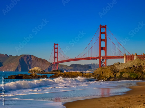 Waves rolling in a the Golden Gate Bridge on Baker Beach just before sunset, San Francisco California, USA