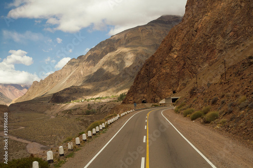 Travel. Asphalt highway in the mountains and valley on the road to mountain Aconcagua in Mendoza, Patagonia Argentina. The road crosses a tunnel in the rocky hill.