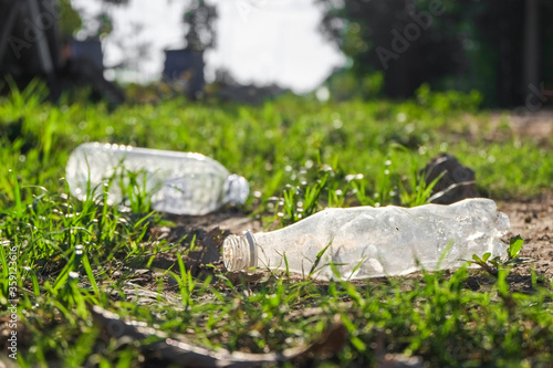 Garbage from plastic bottle that are thrown away on the green grass field in park which is a problem and pollution to the environment close-up.