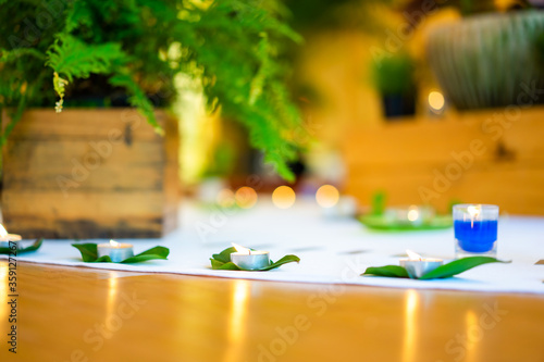 Candle decoration on the wood floow with flower fern and tree on white circle in the middle of woodfloor center inside the hall. photo