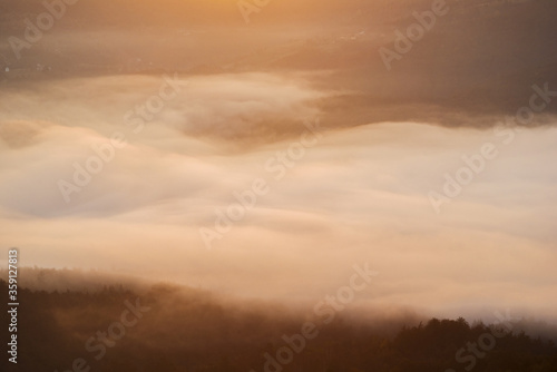 The dense morning mist in the mountain passes through the forest