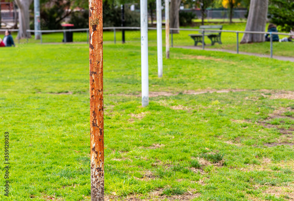 Four Australian football goal posts, one that is very rusted, at a suburban football oval in Brunswick East ,Melbourne, Australia