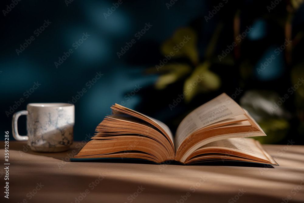 Drinking Coffee and Reading Book Concept. Hot Coffee Cup and Opened Book on Table. Cozy Living Drinking Coffee and Reading Book Concept. Hot Coffee Cup and Opened Book on Table. Cozy Living