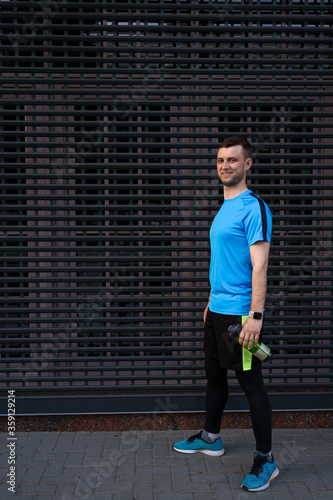 Portrait sporty man on gray urban background. Portrait city runner on a break concentraiting for a long marathon.