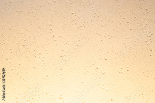 light yellow glass background with raindrops, autumn sunset, texture,