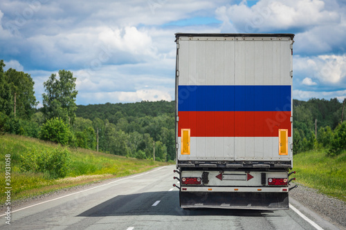 A truck with the national flag of Russia depicted on the back door carries goods to another country along the highway. Concept of export-import,transportation, national delivery of goods