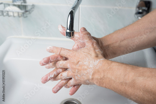 Older male is washing his hand under faucet