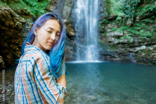 Young woman resting near the waterfall in summer.
