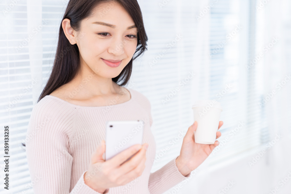 部屋でスマホを見る女性 部屋でスマホを見る女性