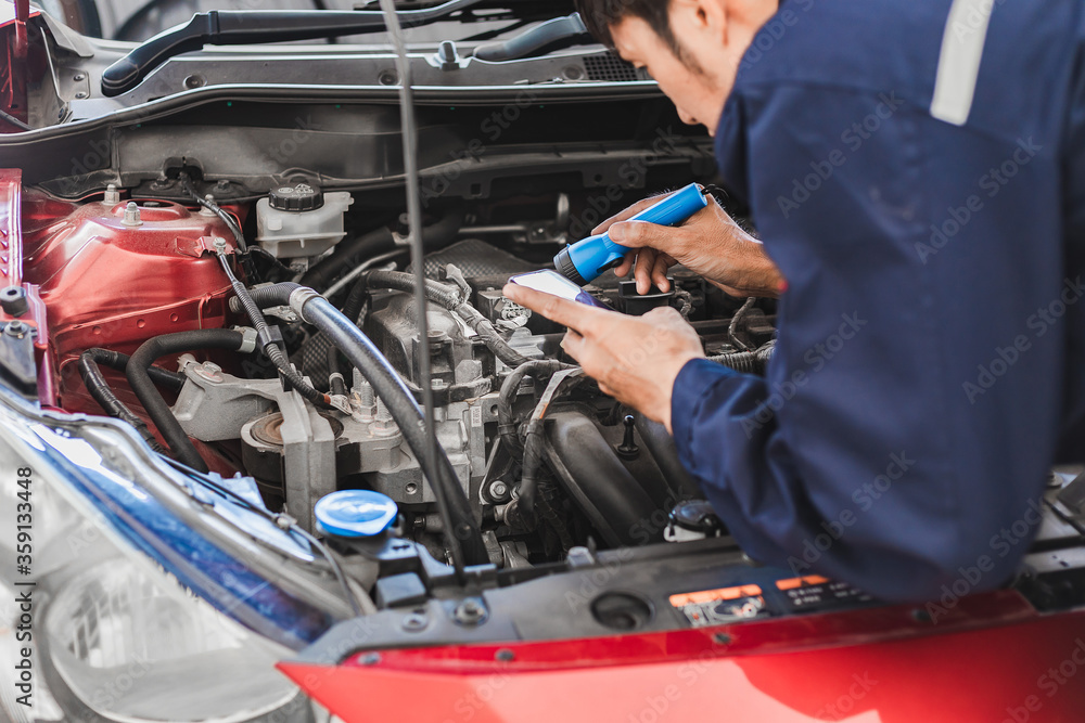 Asian Man mechanic inspection Shine a torch car engine checking bug in engine from application smartphone.Red car for service maintenance insurance with car engine.for transport automobile automotive Asian Man mechanic inspection Shine a torch car engine checking bug in engine from application smartphone.Red car for service maintenance insurance with car engine.for transport automobile automotive