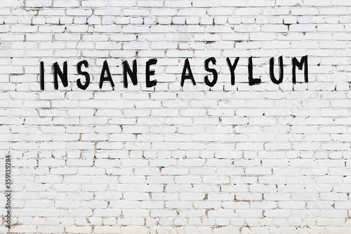 фотографія White wall with black paint inscription insane asylum on it
