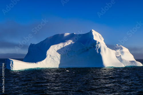Massive non tabular iceberg, amazing and beautiful, lit by warm evening light, with clearing fog, Bransfield Strait, near the South Shetland Islands and Antarctic Peninsula, Polar Regions, Antarctica © Eleanor Scriven 