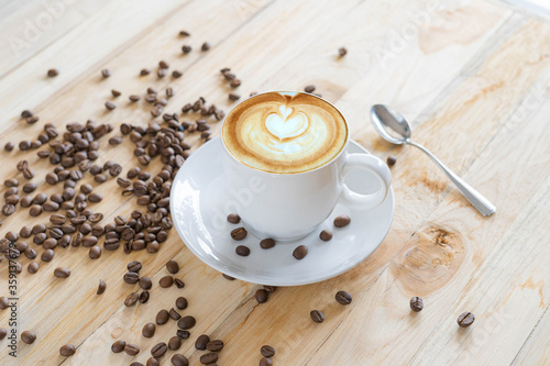 Hot Coffee Latte Art on a wooden table with raw coffee beans soft focus, And free space.