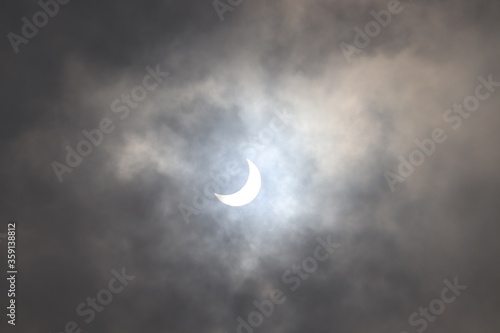 Full and partial Solar Eclipse seen in the cloudy sky.