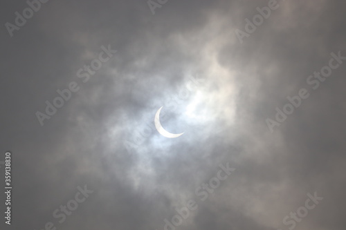 Full Solar Eclipse seen in the cloudy sky.