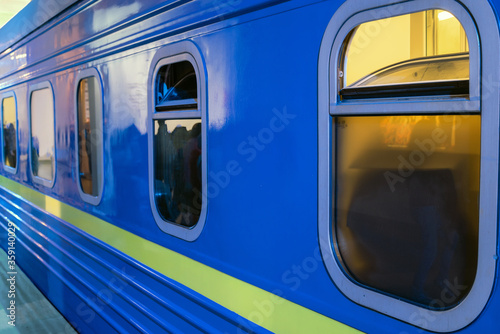 Blue sleeping passenger car stands at the platform. Selective focus.