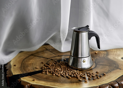 Geyser coffee maker and coffee beans on an oak stand on a background of tulle