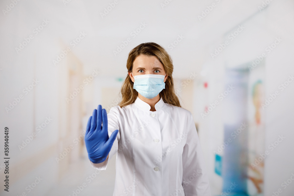 Female doctor in face mask showing stop sign with her hand Female doctor in face mask showing stop sign with her hand