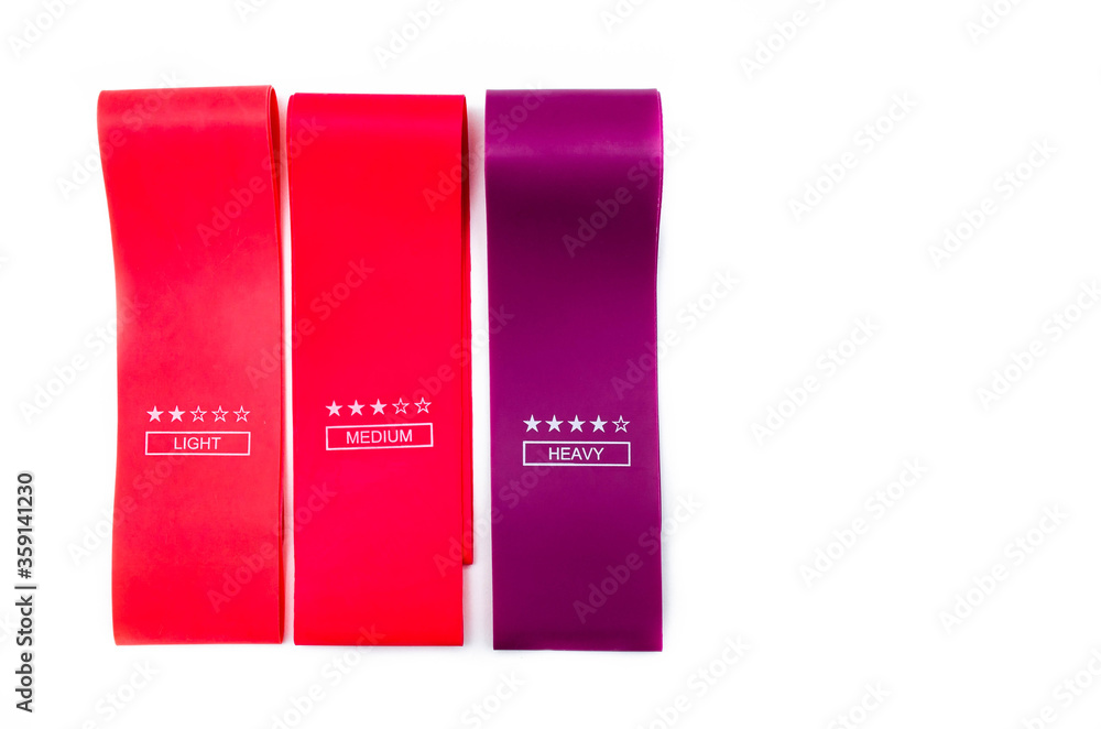 Elastic bands for fitness. Three elastic bands for fitness in close-up on a white background. Erasers lie on the table top and side view. A bunch of rezhinki, twisted into a roll. Elastic bands left 