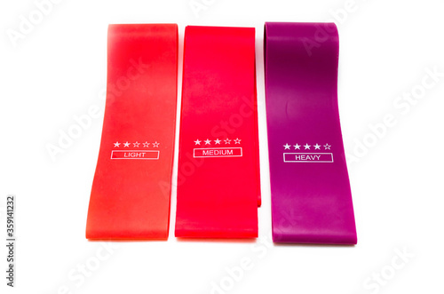 Elastic bands for fitness. Three elastic bands for fitness in close-up on a white background. Erasers lie on the table top and side view. A bunch of rezhinki, twisted into a roll. Elastic bands left 