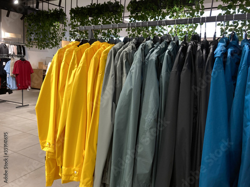 Close-up colorful raincoats on hanging racks in clothing fashion store. Sale casual clothing