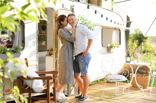 Portrait of young cauacasian wife kissing husband near house on wheels. photo