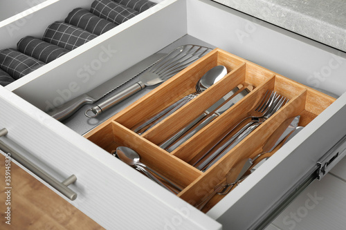 Fotografering Open drawer with different utensils and folded towels