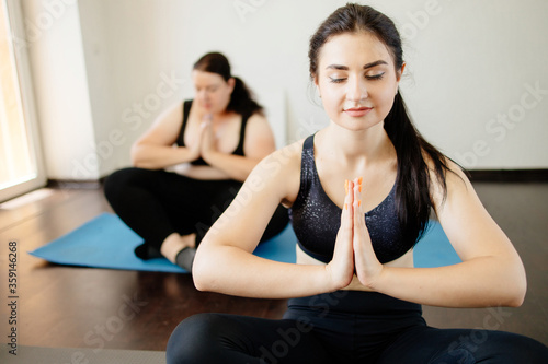 Home yoga studio. Two young women doing yoga exercises meditating at living room. Mindfulness, spirituality and healthy lifestyle concept