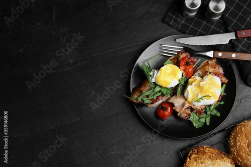 Delicious eggs Benedict served on black table, flat lay. Space for text