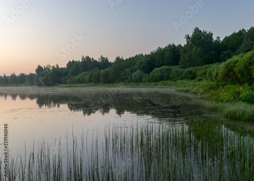 morning landscape with lake, green grass in the foreground, sunrise on the lake, summer