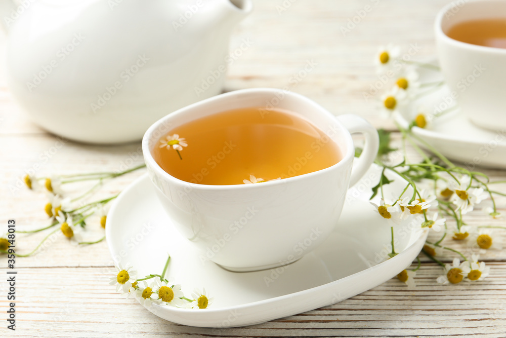Cup of tea and chamomile flowers on white wooden table Cup of tea and chamomile flowers on white wooden table