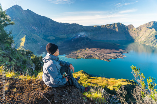 Wallpaper Mural Young Asian man trekker sitting on Sembalun crater in Rinjani active volcano mountain, Lombok island in Indonesia Torontodigital.ca