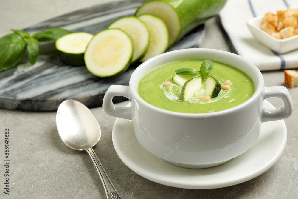Tasty homemade zucchini cream soup served on grey table Tasty homemade zucchini cream soup served on grey table