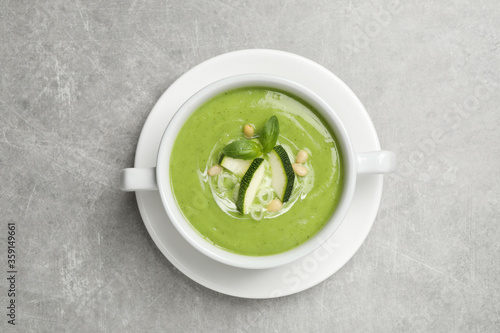 Tasty homemade zucchini cream soup on grey table, top view
