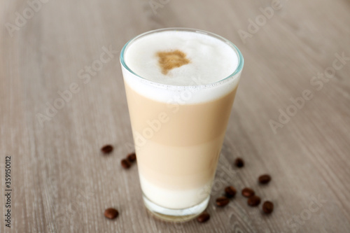 Delicious latte macchiato and coffee beans on wooden table
