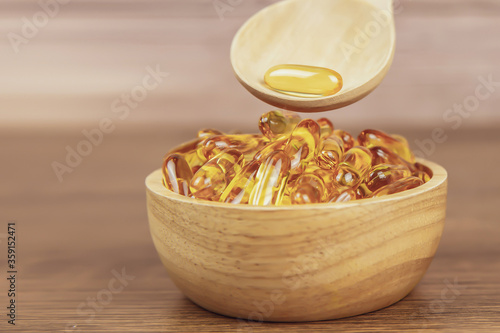 A pile of cod liver oil capsule in a wooden spoon. Dietary supplement for health-care concepts.