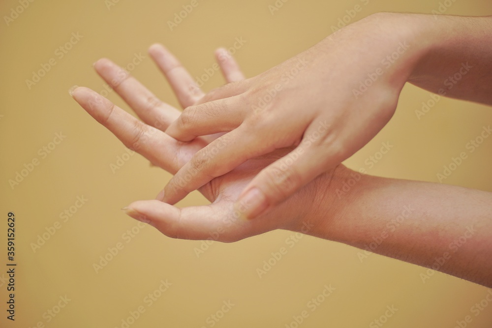 Fototapeta premium Close up of a hand using hand sanitizer with yellow backgorund.