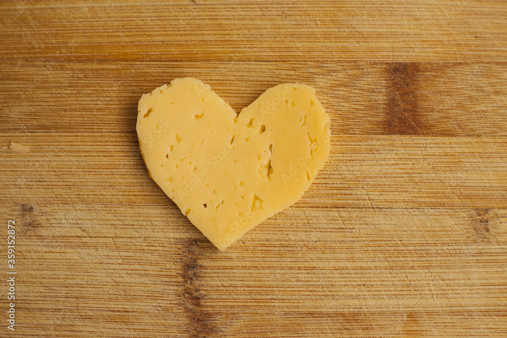 Cheese in the shape of a heart on a wooden Board. Cheese in the shape of a heart on a wooden Board.