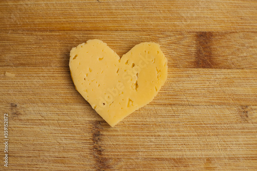 Cheese in the shape of a heart on a wooden Board.