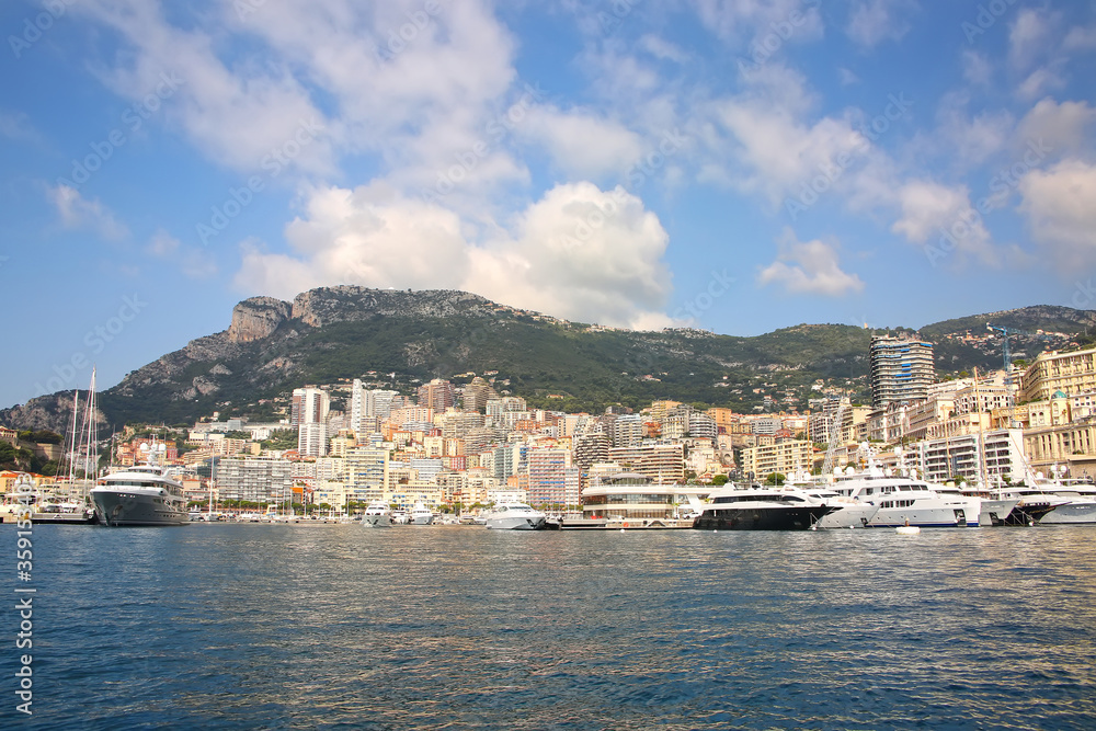 View from the Mediteranean sea of the Principality of Monaco, and Monte Carlo, with dense skyscrappers , the marina, yachts, palace & casino. 