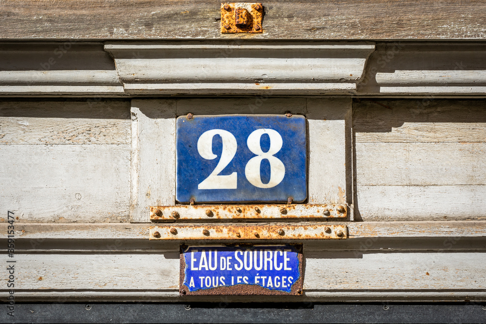 Fototapeta premium Plaque de rue avec numéro 28 et indication d'eau courante de source à tous les étages