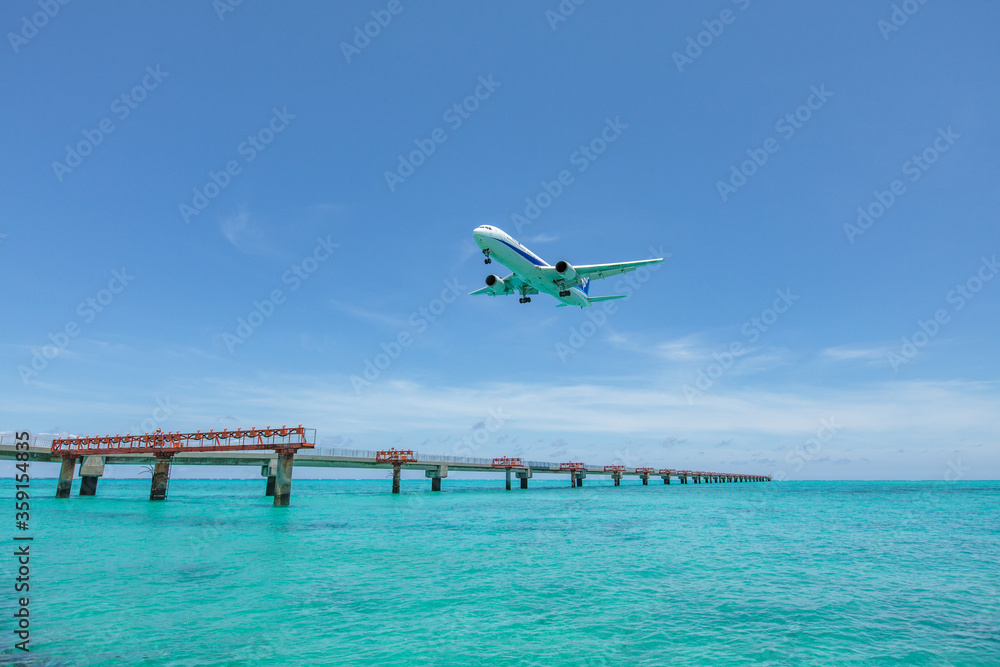 Landing airplane on emelardgreen ocean in summer