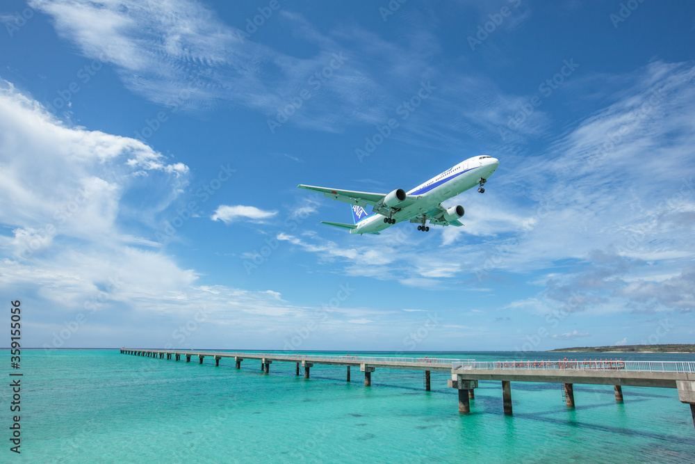 Landing airplane on emelardgreen ocean in summer
