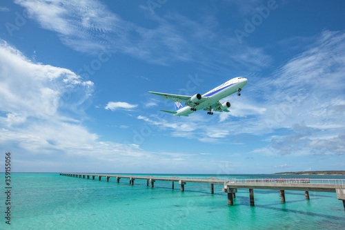 Obraz na płótnie Landing airplane on emelardgreen ocean in summer w salonie