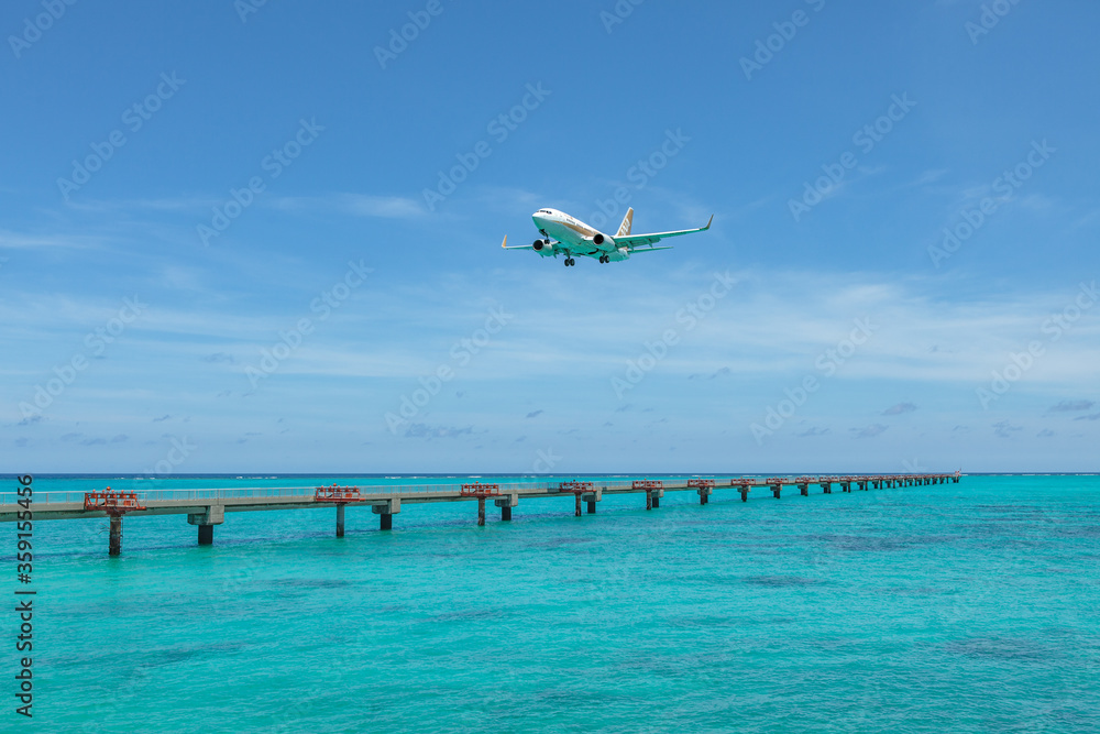 Landing airplane on emelardgreen ocean in summer