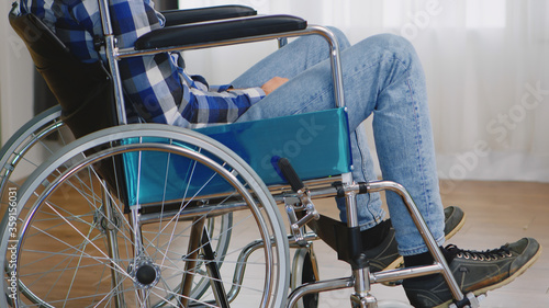 Invalid thoughtful man in wheelchair looking lost on window.