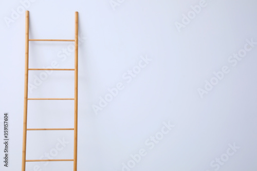 Modern wooden ladder on white background. Space for text